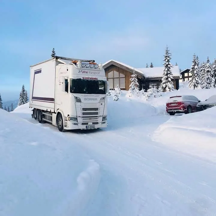 Hvit Volvo lastebil på et snødekt hyttefelt