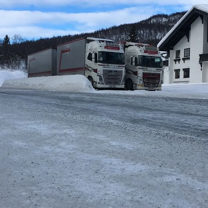 To hvite Volvo-lastebiler fra Utne Transport parkert side ved side på et snødekt område.